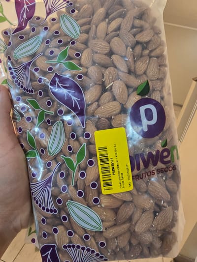 The image shows a bag of Piwen brand natural almonds, 1 kilo, without salt. The Piwen logo is visible on the bag, along with the product information, including the SKU and barcode sticker. The bag is filled with almonds. The background is out of focus, so it is difficult to provide details about the specific location. Based on the Piwen brand availability and the description in Spanish on the label, this image was likely taken in La Florida, Chile.