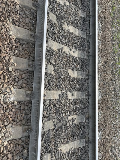 The image shows a section of railroad tracks. The tracks consist of two parallel steel rails resting on concrete sleepers, which are embedded in gravel ballast. The gravel fills the spaces between and around the sleepers. The location is likely near Кечёво, Russia.