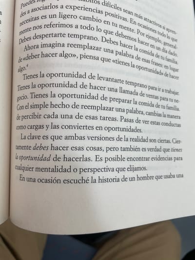 Here's a detailed description of the image:
**Scene:** A close-up shot of a book open to a page of Spanish text. The book appears to be lying on a surface, and part of someone's clothing (likely pants) is visible in the background, suggesting the book is in a casual setting.
**Text Content:** The Spanish text on the page seems to be from a self-help or motivational book. The text discusses changing one's mindset to view obligations as opportunities. Key phrases include: "oportunidad" (opportunity), and a discussion of replacing phrases like "deber hacer algo" ("must do something") with "tienes la oportunidad" ("you have the opportunity"). The final line mentions a story the author once heard about a man.
**Overall Impression:** The image gives the impression of someone reading or studying the book. The focus is on the content of the text, suggesting the importance of the message being conveyed.
**Location in Sant Adrià De Besòs, Spain:** While it is not possible to determine the exact location of the image, I can affirm that the location is not within Sant Adrià De Besòs, Spain. The image is of a book, not a location.