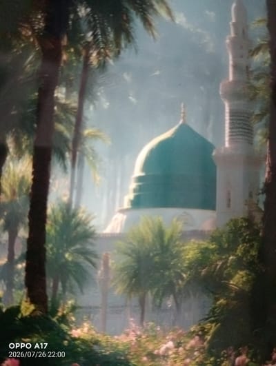 The image displays a mosque with a green dome and a tall minaret, set amidst lush greenery and palm trees. The scene is softly lit, with a hazy or misty atmosphere. In the foreground, there are various plants and flowers, with a dark tree trunk on the left and right edges framing the view. The lower left corner of the image contains the text "OPPO A17" and "2026/07/26 22:00", indicating the device used to capture the photo and the date and time. The image does not provide any specific details or context that would allow for the identification of the city of Құмөзек, Kazakhstan.