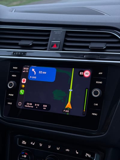 Here is a description of the image:
The image shows the interior of a car, specifically the dashboard area. The car's navigation system is active, displaying a map with a route. According to the navigation, the vehicle is currently traveling at 83 km/h, with a speed limit of 90 km/h. The navigation indicates that the destination, P-243, is 32 km away and that the estimated arrival time is 23:35, taking 3 hours and 12 minutes. The remaining distance to the destination is 326 km. The temperature outside is 24 degrees, and the temperature inside the car is set to 20 degrees. The passenger airbag is on.