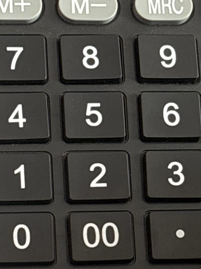 The image is a close-up, high-angle shot of a calculator keypad. The keypad is black with white numbers and symbols. From top to bottom, and left to right, the visible keys are: M+, M-, MRC, 7, 8, 9, 4, 5, 6, 1, 2, 3, 0, 00, and a decimal point. The lighting is even, and the focus is sharp on the keys. There are no people or other environmental elements visible in the image, and therefore no indication of location in Jrarat, Armenia.