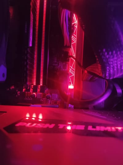 This image shows the interior of a computer case, illuminated by red and purple LED lighting. The components visible include RAM modules with red lighting, cables, and what appears to be a motherboard. In the foreground, a surface with the text "PUSH THE LIMIT" is lit by three small red lights. The scene is dark, with the lighting from the computer components creating a vibrant, almost neon glow. There are no people or indications of the city of Roranwala, Pakistan.