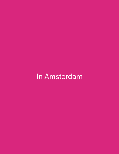 The image displays a solid magenta background. Centered horizontally and vertically on this background is white text that reads "In Amsterdam". No people, additional subjects, or objects are present within the image. The environment is abstract, defined solely by the uniform magenta color. The location for this scene is Breda, Netherlands.
