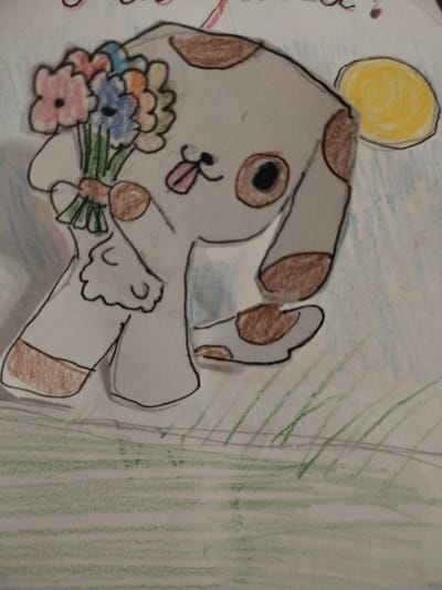 The image is a drawing on paper depicting a stylized, cartoonish dog holding a bouquet of colorful flowers. The dog is white with brown spots on its ears, tail, and paws, and has large, round eyes, one of which is a bright yellow circle. It has a pink tongue sticking out. The flowers are a mix of pink, blue, orange, and yellow. The background is a light blue, suggesting sky, with some green scribbles that could represent grass. The drawing appears to be a child's artwork. There is no discernible location in the city of Акбердино, Russia, depicted in the image.