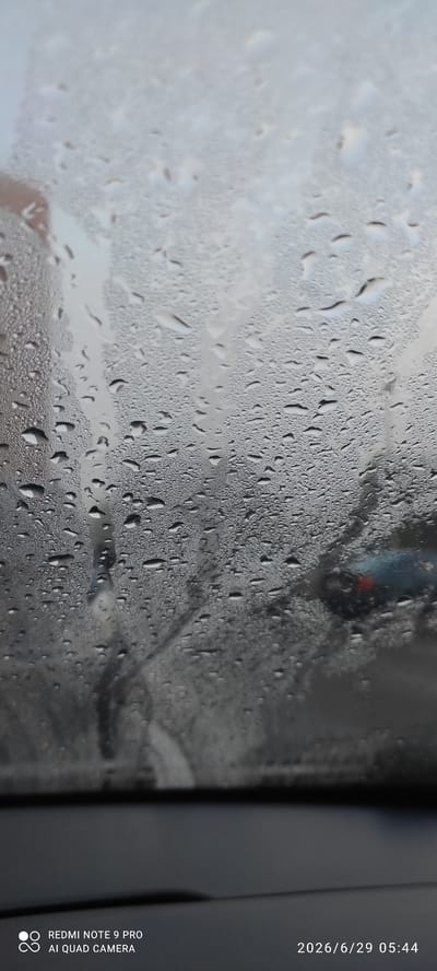 A close-up shot captures a car windshield covered in water droplets, obscuring the view of the exterior. The droplets vary in size, with some forming larger streaks. In the background, a blurred image of a blue car with a red light is visible, possibly indicating traffic. The lower portion of the image shows the interior of the car, with a dark dashboard. The timestamp in the bottom right corner indicates the image was taken on June 29, 2026, at 05:44. Text at the bottom left reads "REDMI NOTE 9 PRO AI QUAD CAMERA". While the location is identified as Maardu, Estonia, there are no specific visual cues in the image to confirm this.