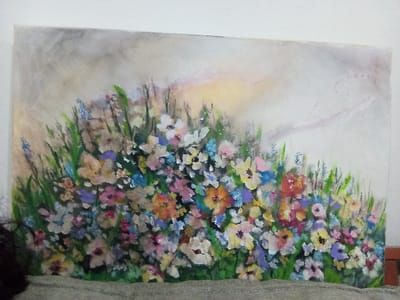 A canvas painting depicts a vibrant, colorful meadow. A multitude of wildflowers in varying hues of white, blue, pink, orange, and yellow are clustered together. Green stems and blades of grass rise among the blooms. The background is a soft blend of beige and gray, with hints of pale yellow suggesting a distant light source, possibly the sun. The painting gives an impressionistic feel with blurred details.