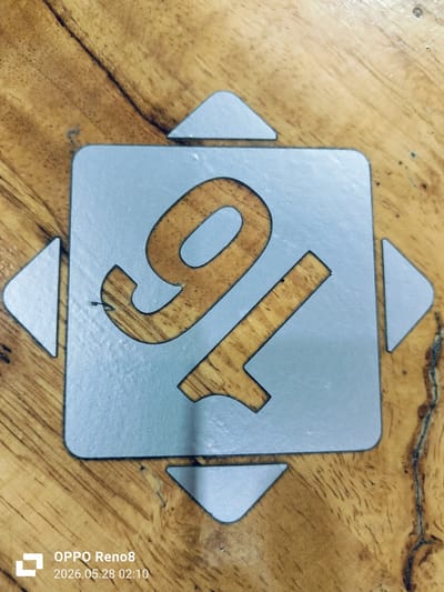 The image shows a light-blue stencil of the number "91" overlaid on a wooden surface. The stencil is square with an arrow-shaped extension pointing outward from each side. The underlying wood is light brown with visible grain. The photo was taken with an OPPO Reno8 and the timestamp indicates May 28, 2026 at 02:10. No information connects this image to Cempeudak, Indonesia.