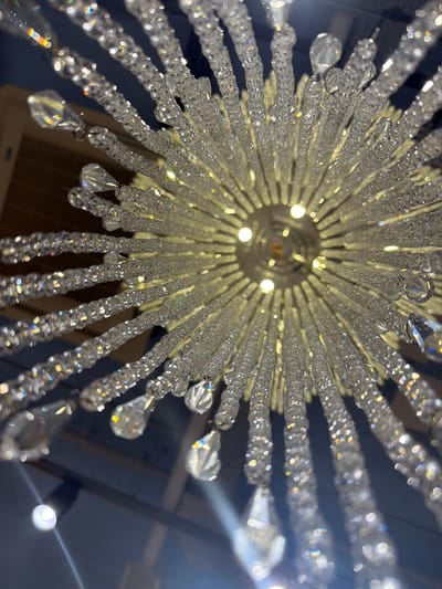A low-angle shot of a crystal chandelier with multiple tiers and strings of crystals. The light fixture is suspended from the ceiling and the perspective looks upward towards the center, where light bulbs are visible. The crystals refract light, creating a sparkling effect.
I have no information indicating that this image was taken in Spreitenbach, Switzerland.