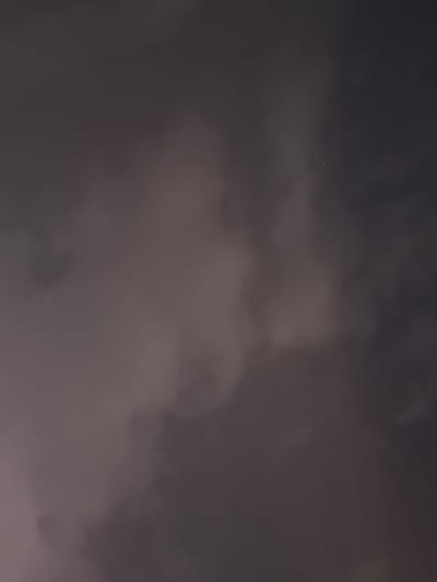 The image shows a dimly lit, cloudy night sky with a small, bright object visible near the center. The object appears to be a single point of light, possibly a star or a planet. The clouds are dark and diffused, suggesting they are obscuring most of the sky. There are no discernible structures or features of the city of Hisor, Tajikistan visible in this close-up shot of the sky. The overall impression is of a quiet, possibly overcast night.