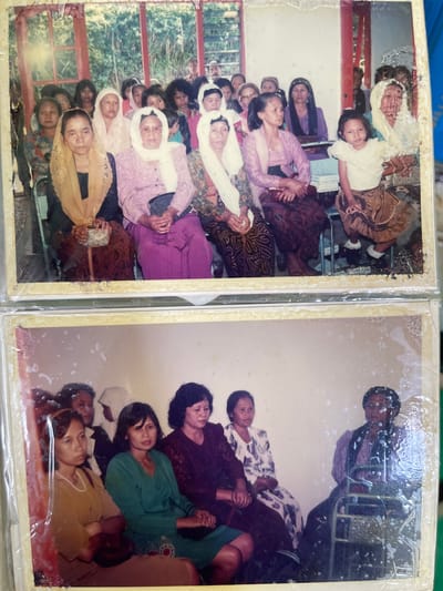 Two adjacent photographs in a photo album. The left photograph shows a gathering of approximately 20 women and one young girl indoors near a window. Many of the women are wearing head coverings. One woman holds a small beaded purse. The right photograph shows a gathering of approximately seven women indoors. An African American man stands against a wall at the top of the frame. The location may be Pagerkukuh, Indonesia.