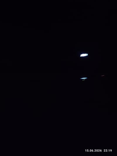 The image shows a dark, nighttime scene with several blurred, illuminated streaks of light. In the upper right quadrant, there is a bright white streak of light. Below and slightly to the left of this, there is a horizontal streak of blue and green light. Further to the right and lower, a thin red streak is visible. In the bottom right corner, a timestamp reads "15.06.2026 22:19". The background is entirely black, indicating a very dark environment with limited ambient light. The nature of the light streaks suggests movement, possibly from vehicles or other light sources captured with a long exposure or due to motion blur. Without further context or clearer visual elements, it is not possible to determine the specific location within Synelnykove, Ukraine, or the exact nature of the objects or events causing these light streaks.