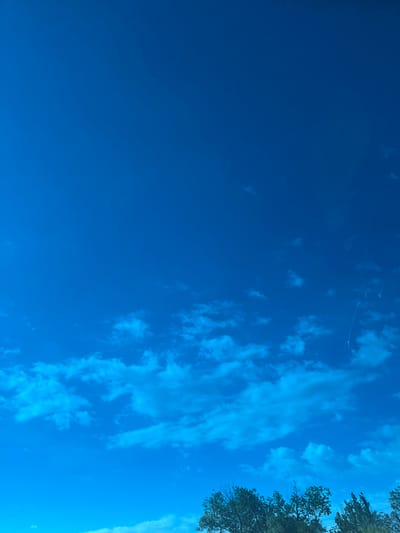 The image depicts a sky with varying shades of blue, with sparse clouds and a small amount of tree cover in the upper right corner. Location information for Tlustenkhabl, Russia, is not available.