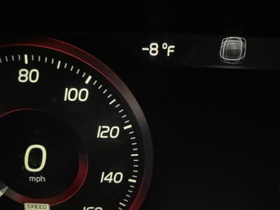 The media file displays a close-up of a digital car dashboard, likely an instrument cluster. The primary subject is a speedometer on the left side of the frame, indicating the vehicle's speed. The speedometer shows a large "0 mph" in the center, signifying the car is currently stationary. Around this, an arc-shaped scale marks speeds in increments of 20, with numbers like "80", "100", "120", and "140" clearly visible. A thin red ring outlines a portion of the speedometer, possibly indicating a dynamic element or design choice.
To the upper right of the speedometer, an external temperature reading is prominently displayed as "-8 °F" (minus eight degrees Fahrenheit), indicating extremely cold weather conditions. Adjacent to the temperature, a distinctive graphical icon or indicator is visible, appearing as a square composed of several concentric, slightly offset lines or rings.
At the very bottom edge of the frame, partially obscured, the words "SPEED LIMIT" can be faintly seen. The overall background of the display is black, with the numbers, text, and graphics illuminated in white, except for the red accent on the speedometer. The image suggests a cold day or night in Montgomery, United States, given the very low temperature reading.