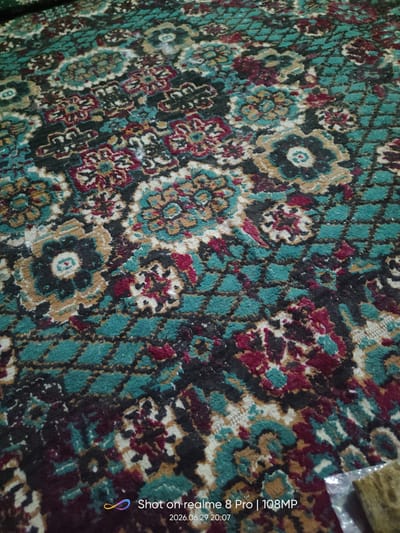 The image displays a close-up view of a carpet with a traditional floral and geometric pattern. The dominant colors are teal, maroon, black, and beige, with accents of white and gold. The carpet appears to be made of a textured material. The bottom right corner of the image contains a watermark indicating it was "Shot on realme 8 Pro | 108MP" with the date "2026.06.29 20:07". The scene is captured indoors, likely on a floor, and there are no people or specific landmarks visible that would indicate a location within the city of Bokhtar, Tajikistan. The lighting suggests an indoor setting, possibly with artificial light.