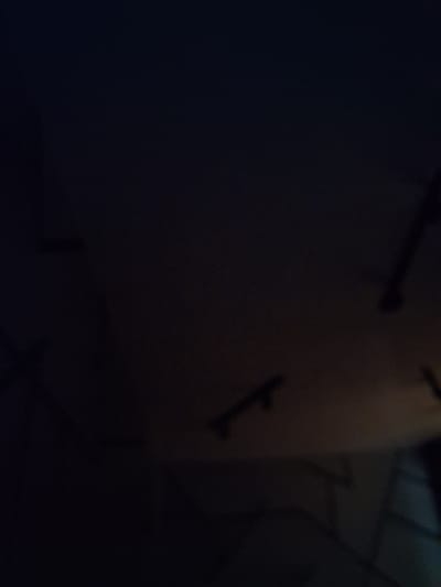 The image is a dark, blurry photograph that appears to be taken indoors. The lighting is dim, and the focus is poor, making it difficult to discern specific details. In the upper right quadrant, a dark, elongated object, possibly a structural element or a piece of equipment, is visible against a lighter, out-of-focus background. There are also indistinct shapes and shadows scattered throughout the frame, suggesting a cluttered or dimly lit environment. The overall impression is one of low light conditions and limited visibility. There is no discernible information in the image that would suggest its location in Volokolamsk, Russia.