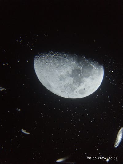 The image is a photograph of the moon partially illuminated against a dark sky filled with stars. The moon displays visible craters and surface features. In the lower right corner of the image, a timestamp is present: "30.06.2026 06:07". There are no identifiable people, animals, or structures visible in the image, and therefore no specific location in TashGRES, Uzbekistan can be determined from the visual content alone. The image appears to be a celestial observation.