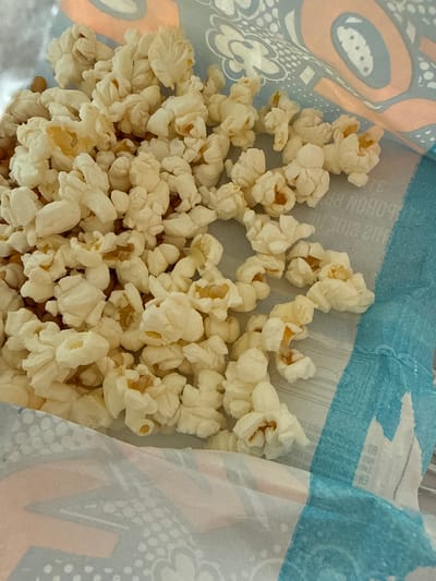 The image shows a bag of popcorn. The bag has a blue and white design with floral and geometric patterns. The popcorn is light yellow and fills a portion of the bag. The location, Vorontsovo, Russia, cannot be determined from the visual information provided.
