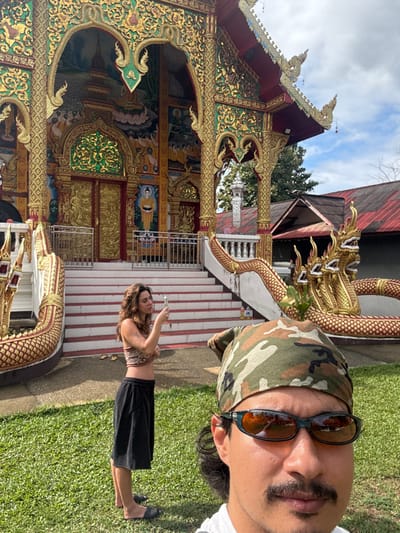 A rotated selfie at a Thai temple captures a man in a camouflage bandana and sunglasses, juxtaposed with the ornate temple architecture. A woman stands in front of the temple, taking a photo. A golden dragon statue adorns the staircase. The scene blends personal snapshots with cultural landmarks, creating a travelogue-style image.