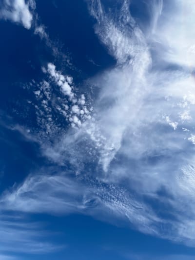 This media file is a close-up, high-angle shot of a deep blue sky filled with white clouds. The clouds are varied in texture and density, ranging from wispy, feathery cirrus clouds to more textured, scattered cumulus clouds. Some areas of the sky are a brilliant, cloudless blue, while others are dramatically filled with white formations. The lighting suggests it is daytime, with the sun illuminating the clouds from above, creating bright whites and soft shadows. The overall impression is one of a dynamic and expansive sky, possibly indicative of fair weather with some atmospheric activity. There is no discernible text or human presence in the image. The location context provided is Dunuisce, Ireland, suggesting the scene is set in a coastal or rural area given Ireland's geography. The image evokes a sense of openness and natural beauty.