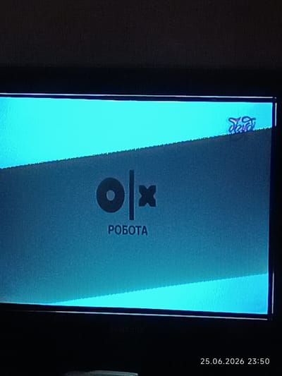 This media file shows a close-up of a television screen displaying a graphic with a logo and text. The dominant colors are bright cyan and dark blue-grey. The screen exhibits some digital distortion or noise, particularly along the top and bottom edges, and a diagonal line of distortion across the middle.

The primary graphic features a logo that appears to be "olx" rendered in a stylized font, with "ol" appearing as a circular shape and a vertical line, and "x" as a separate, blocky character. Below the logo, the word "РОБОТА" is displayed in uppercase letters. In the upper right corner of the screen, a small, somewhat distorted logo or graphic is visible, appearing to be in a purple hue with some lighter colored elements. The overall presentation suggests a loading screen or an informational graphic for a service.

The setting is indoors, as indicated by the presence of a television screen. There are no people visible in the frame. The time stamp at the bottom right of the image reads "25.06.2026 23:50," suggesting the image was captured at night. The location context is Bolhrad, Ukraine. There are no cues about weather or specific emotions, beyond the generic feel of a digital interface. The branding visible, "olx," is a well-known online marketplace.