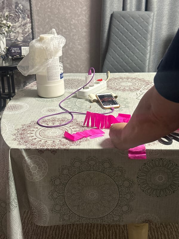 Person crafts colorful piñata at home while caring for babies