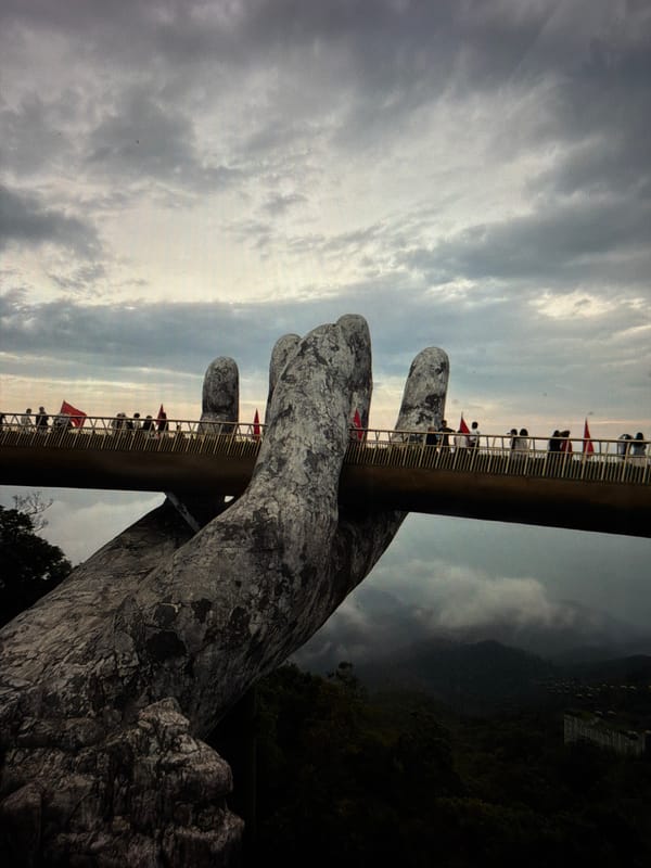 Visitors walk Golden Bridge amid flags at Đà Nẵng tourist site