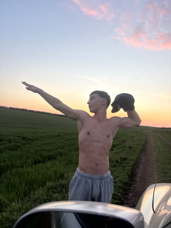 Man poses with car in Bulgarian field at sunset