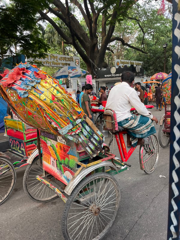 Decorated and loaded rickshaws navigate Dhaka street traffic