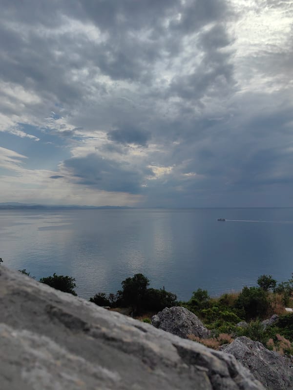 White boat cuts through calm water beneath a cloudy sky