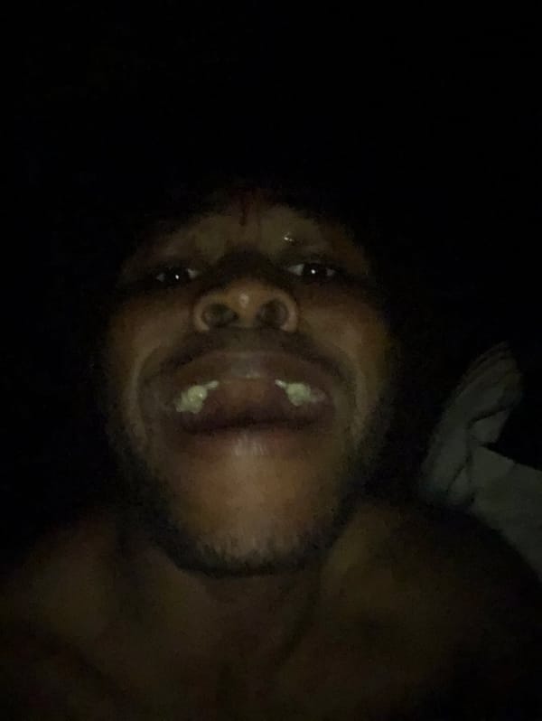 Man photographed making animated expressions in low-light selfie session