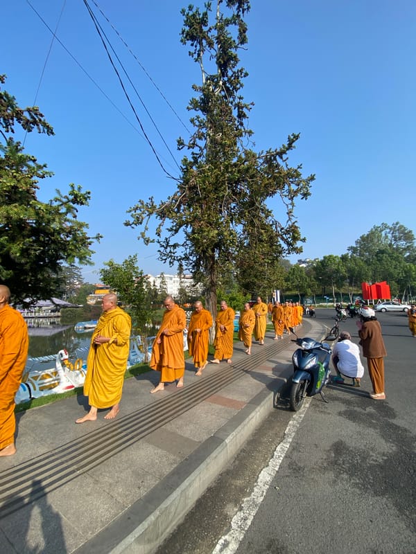 Buddhist monks kneel in street ceremony beside Da Lat lake