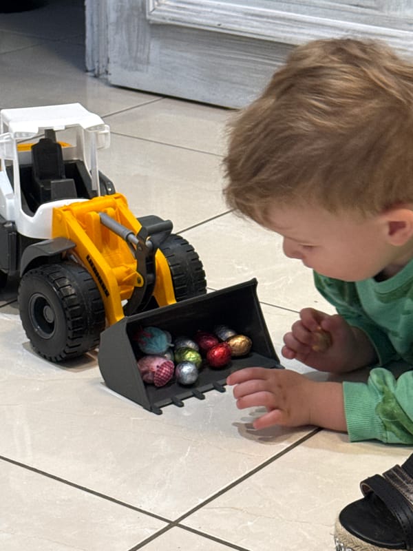 Child plays with Easter eggs and toy trucks