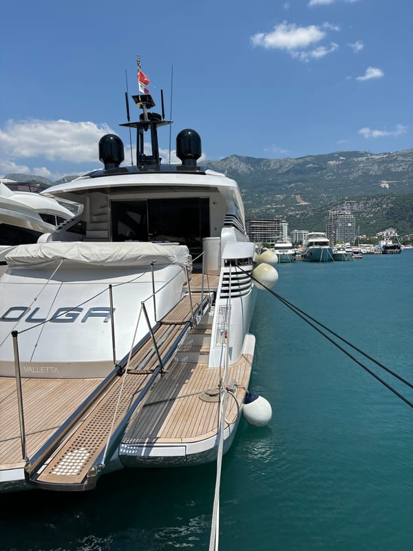A busy morning at Budva's marina — yachts, cranes, and promenade life.