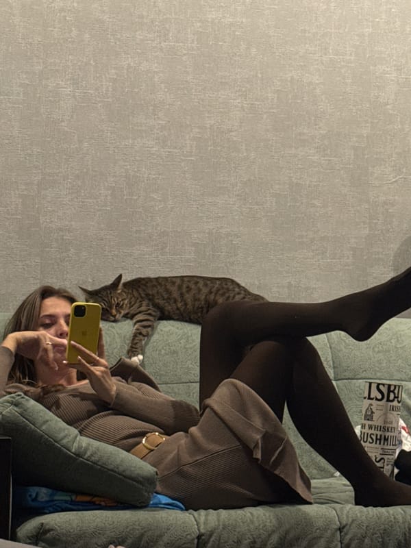Woman takes selfie with cat on sofa in Krasnoyarsk