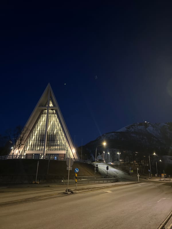 Nighttime photography documents Tromsø's modern architecture against Arctic mountains