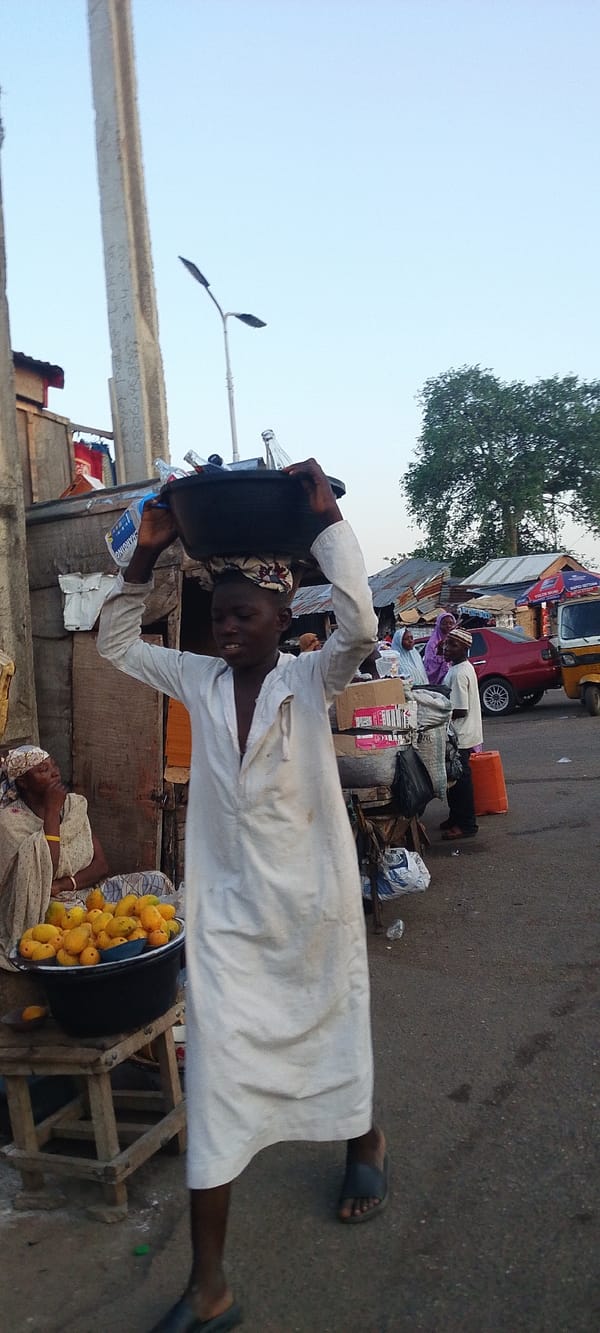 Street vendor carries bottles in Lokoja market area