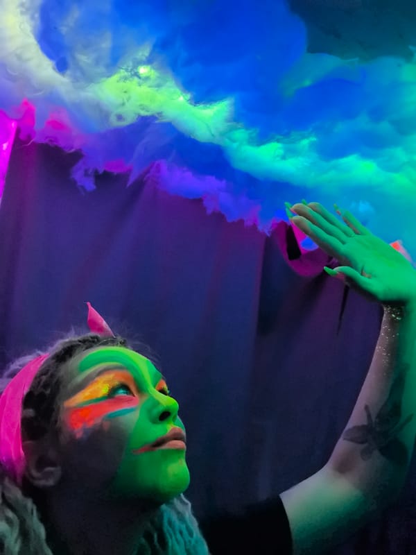 Person in neon face paint interacts with art installation