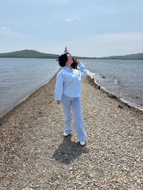 Woman relaxes on rocky Vladivostok beach near lighthouse