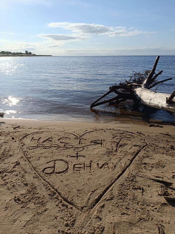 Birthday message written in sand at a waterside beach.