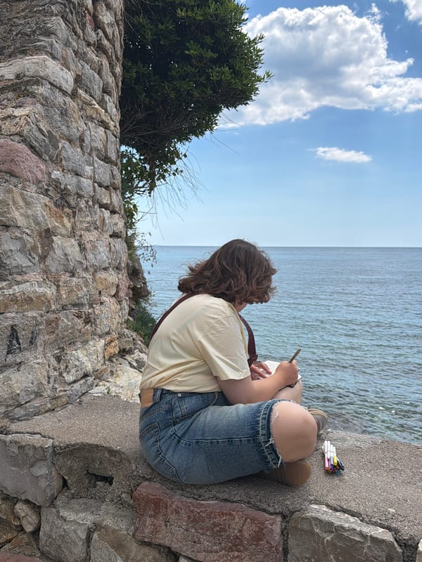 Artist sketches seaside scene on stone wall in Budva