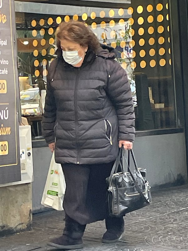 Elderly woman walks Buenos Aires sidewalk carrying bag