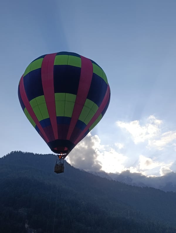Colorful hot air balloon soars over Himalayan mountains in Vashisht