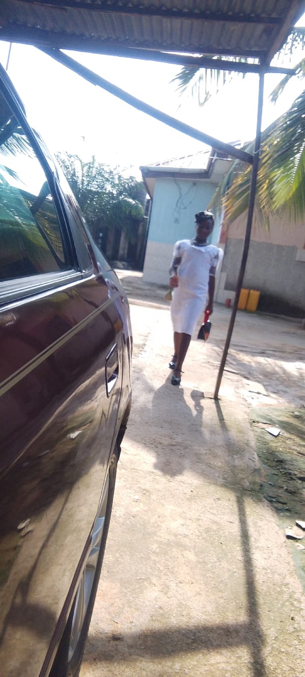 White-dressed group near a maroon sedan in Madalla