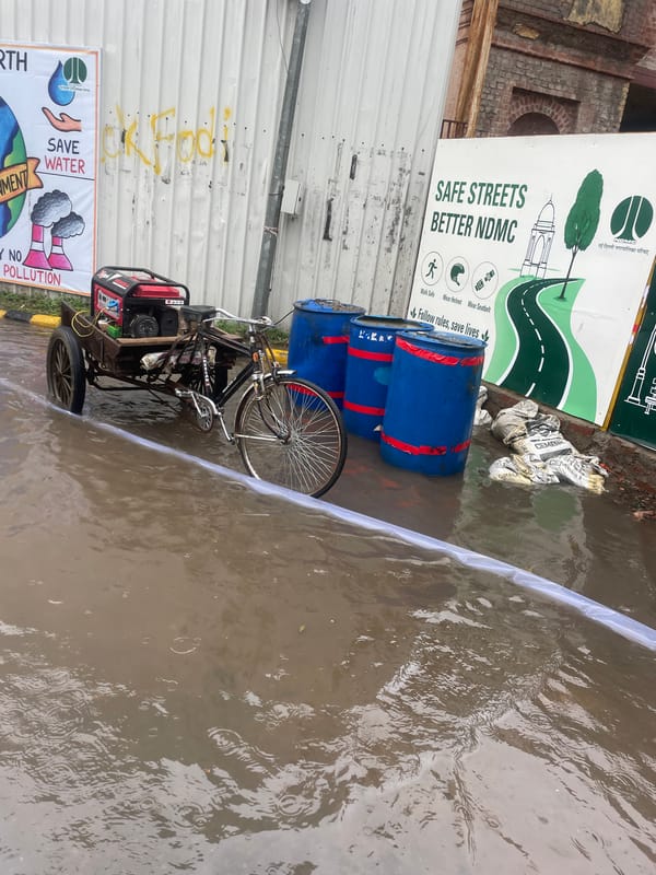 Flooded New Delhi street with submerged cart and active water pump