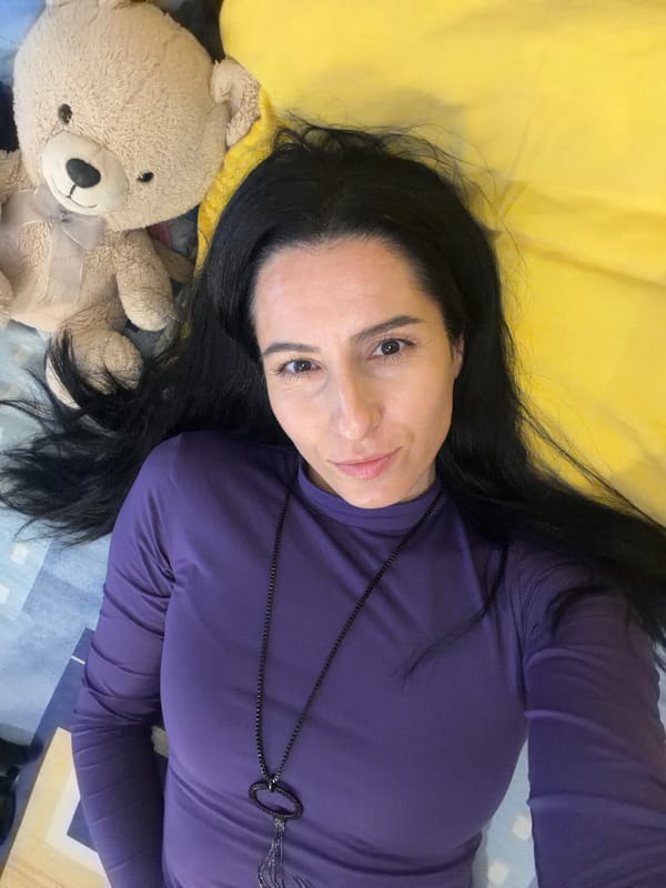 Woman poses with teddy bear on bed in Bulgaria