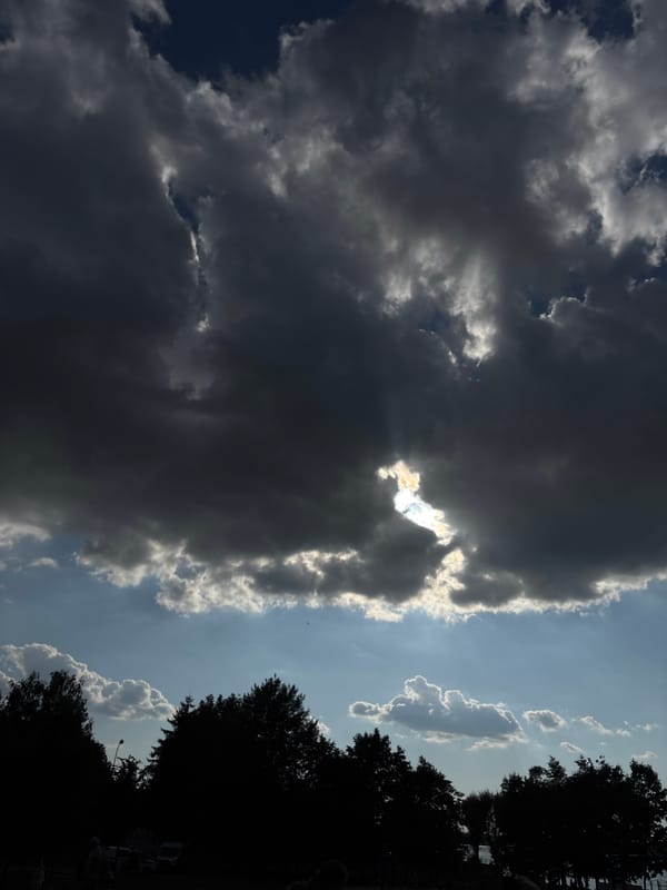 Storm clouds and sunlight compete across a dramatic sky.