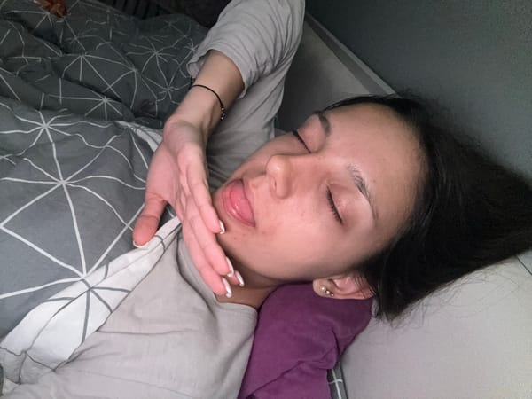 Woman relaxes in bed with snacks and laptop in Sofia