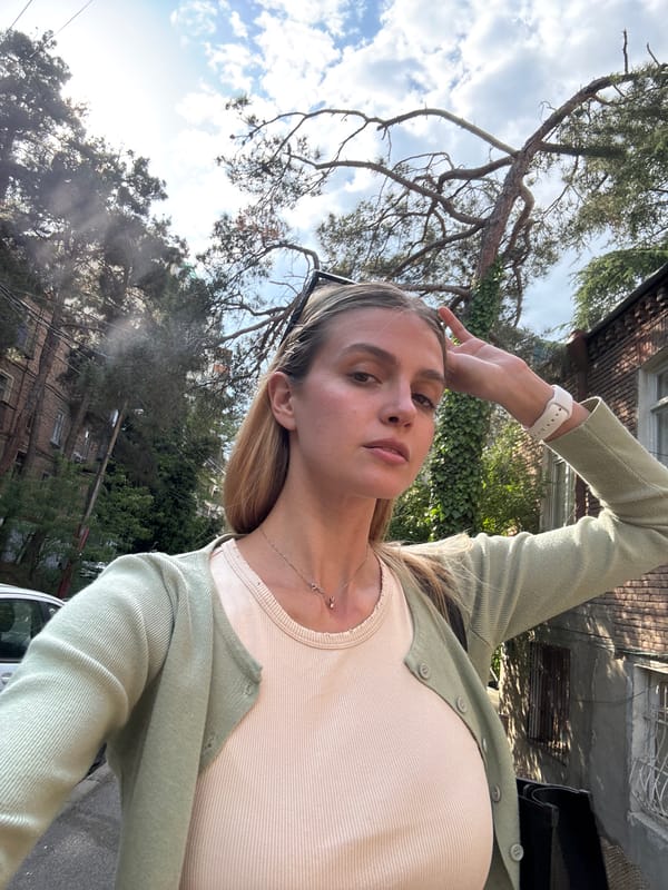Woman takes selfies near brick building in Tbilisi