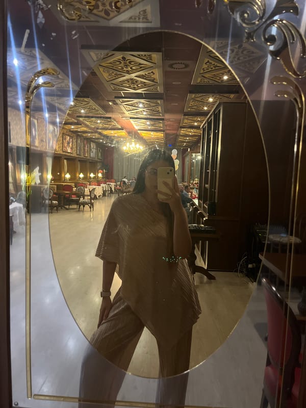 Woman takes selfie in ornate gold mirror at decorated venue